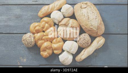 Mit Brotsorten auf verwitterter blau-grauer Planke, knusprigem Brotlaib, Baguettes und Samenbrötchen Stockfoto