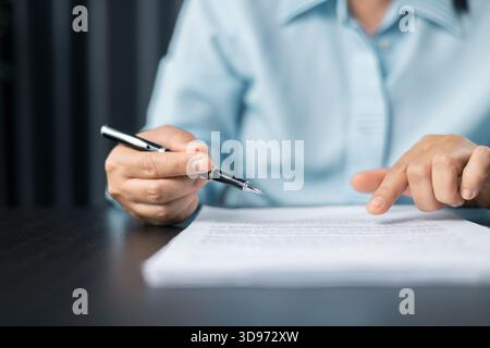 Frau unterschreibt ein Dokument, konzentriert sich auf weibliche Hand, hält Stift, unterschreibt die offizielle Zeitung. Schließen Sie eine Geschäftsfrau, die Dokumente unterzeichnet. Die Hand der Frau Stockfoto