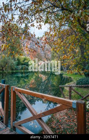 Herbstblick über den reflektierenden Teich, eingerahmt von goldenen Blättern und hölzernem Geländer Monasterio de Piedra Naturpark Saragoza Aragon Stockfoto