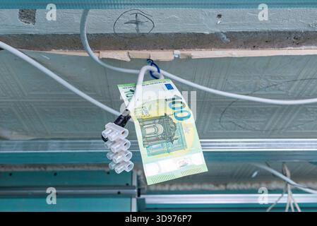 Elektroinstallation für die Renovierung der Beleuchtung, 100 Euro Papierschein hängt an Drähten in einer alten Wohnung, Renovierung der Beleuchtung von Wohnwohnungen mit Stockfoto