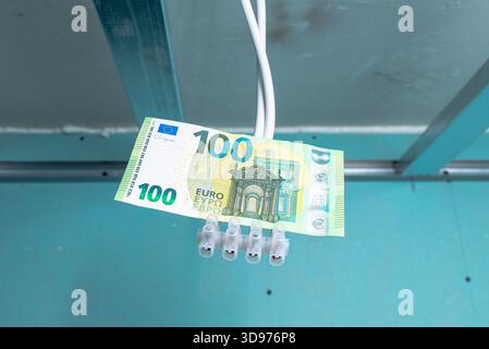 Elektroinstallation für die Renovierung der Beleuchtung, 100 Euro Papierschein hängt an Drähten in einer alten Wohnung, Renovierung der Beleuchtung von Wohnwohnungen mit Stockfoto