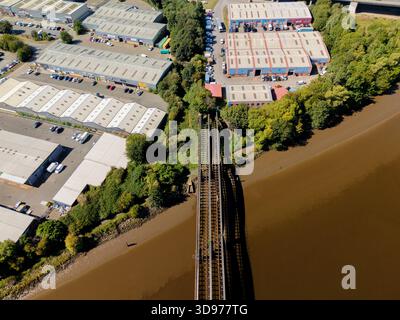 Blaydon on Tyne UK: 15. August 2025: Alte Eisenbahnbrücke in Richtung Blaydon Industrial Estate, mit verschiedenen Lagerhäusern und Gewerbeeinheiten inmitten von Gree Stockfoto