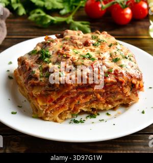 Lasagne mit Hackfleisch, Ricotta und Tomatensauce auf weißem Teller auf Holztisch. Nahansicht Stockfoto
