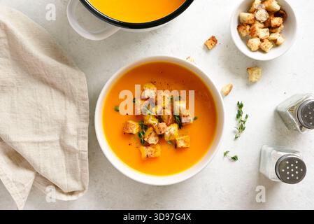 Köstliche Kürbissuppe, garniert mit Croutons und Thymian in einer Schüssel auf hellem Hintergrund. Draufsicht, flach Stockfoto