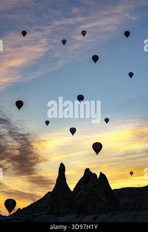 Blick auf Heißluftballons, die bei Sonnenaufgang heiter schweben, vor dem Hintergrund farbenfroher Himmel und Felsformationen, Love Valley, Kappadokien, Türkei. Stockfoto