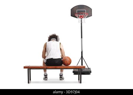 Rückansicht eines enttäuschten Basketballspielers, der auf einer Bank auf weißem Hintergrund sitzt Stockfoto