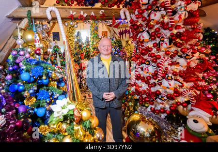 Hannover, Deutschland. Dezember 2025. Thomas Jeromin steht zwischen den Weihnachtsbäumen in seinem Haus im Stadtteil Schaumburg. 621 Weihnachtsbäume mit weit über 125.000 Weihnachtskugeln und 50.000 Lichtern: Das Haus der Familie Jeromin erstrahlt in der Adventszeit wie eine farbenfrohe Weihnachtswelt. Das Rekordinstitut für Deutschland hat die Familie „für die am meisten dekorierten Weihnachtsbäume an einem Ort“ ausgezeichnet. Quelle: Julian Stratenschulte/dpa/Alamy Live News Stockfoto