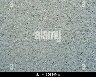 Raue Betonwand mit Kieselsteinen und unregelmäßiger Textur.Nahaufnahme. Copyspace. Stockfoto