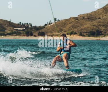 Muskulöser Mann Wakeboarding auf See im Sommer Stockfoto