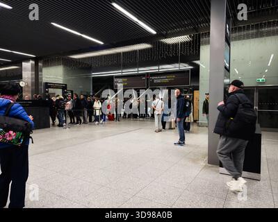 Krakau, Polen - 07. November 2025: Viele Reisende stehen mit Gepäck an einem geschäftigen Sicherheitskontrollpunkt am Flughafen Polen Krakau in einem modernen Terminal an. Stockfoto
