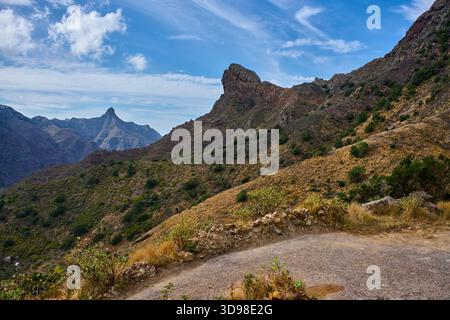 Unbefestigter Wanderweg schlängelt sich durch vulkanische Berglandschaften mit dem dramatischen Gipfel des Roque Taborno, der in der Entfernung von den Anaga Mountains Teneriffa zu sehen ist Stockfoto