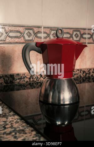 Schöne rote Mokafeemaschine, die Kaffee auf Glaskeramikkochfeld brütet. Wohnküche Inneneinrichtung mit Kopierraum. Stockfoto