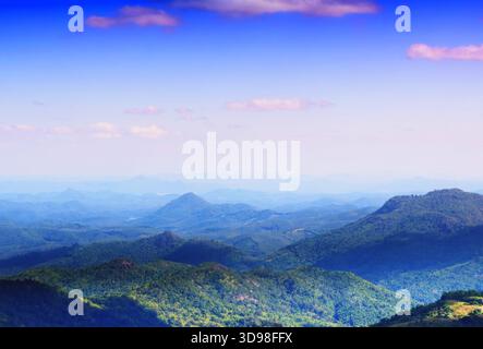 Ein Blick auf die Berge, die von üppigen Wäldern bedeckt sind, und einen klaren blauen Himmel. Stockfoto