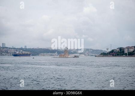 Blick auf den Bosporus mit dem Maidens Tower unter bewölktem Himmel während des Tages in Istanbul, mit Blick auf maritime Aktivitäten und städtische Landschaft Stockfoto