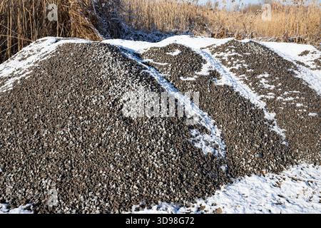 Schotterpfähle mit leichtem Winterschnee in der Landschaft des industriellen Außenlagers Stockfoto
