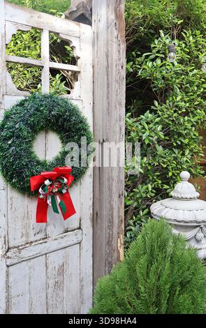 Weiße Holzzaun-Tür mit Weihnachtskranz dekoriert Stockfoto