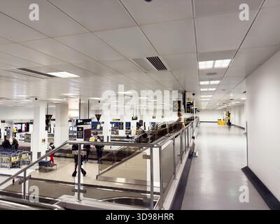 Manchester, Großbritannien - 07. November 2025: Überfülltes Flughafeninnere in Manchester mit Schildern, Kiosken und Passagieren, die sich durch ein helles Terminal bewegen. Stockfoto