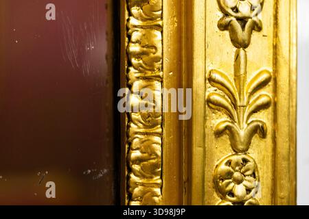Exquisit detaillierter vergoldeter Rahmen mit erhöhten Blumenmotiven und komplizierten Scrollarbeiten. Perfekt für luxuriöse Innenräume, klassisches Dekor oder antike Pho Stockfoto