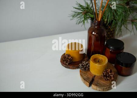 Wachskerzen auf einem hölzernen Kerzenhalter in der Nähe von grünem Tannenzweig. Großaufnahmeblick-Feiertagskonzept mit weißem leerem Kopierraum. Nat Stockfoto