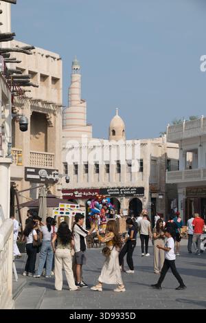 Besucher genießen die lebhafte Atmosphäre von Souq Waqif und erkunden Geschäfte und Stände unter einem klaren blauen Himmel. Stockfoto