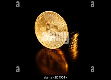 Bitcoin-Münze isoliert auf schwarzem Hintergrund. Stapel Goldmünzen mit Bitcoin-Münze davor. Goldener Bitcoin, Kryptowährung. Kryptowährung. Stockfoto