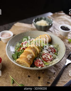 Restaurant-Frühstücksmenü-Konzept, Roll-Omelette gefüllt mit Käse serviert auf frischem Salat Stockfoto