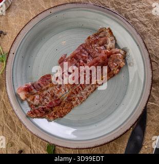 Gebratenes Speckstück zum Frühstück oder eine Beilage auf einem handgefertigten Teller Stockfoto