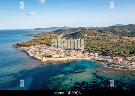 Blick Aus Der Vogelperspektive Auf Das Küstendorf Mit Hafen, Türkisfarbenem Wasser Und Rolling Hills, Sardinien, Italien Stockfoto