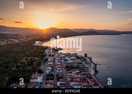 Sonnenuntergang über dem Küstendorf aus der Vogelperspektive mit Bergen, ruhigem Meer und Golden Hour Light, Sardinien, Italien Stockfoto