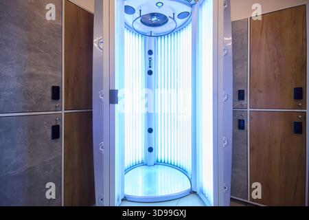 Spa-Behandlung, moderne Bräunungsräume, UV-Kabine mit Holzschrankablage, Inneneinrichtung im klinischen Stil mit blauem UV-Licht Stockfoto