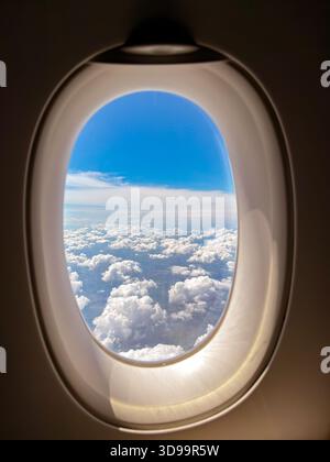 Wolkenlandschaft durch das Fenster eines Urlaubsjets. Keine Personen. Stockfoto