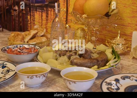 Festlicher Nauryz-Tisch mit Beshbarmak, Sorpa, Salaten, Obst und Wodka in Karaffe. Stockfoto
