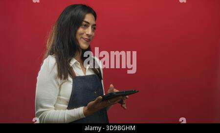 Junge hispanische Frau mit Tablet und Hand im roten Studio; Vertrauen beim Kundenservice. Stockfoto