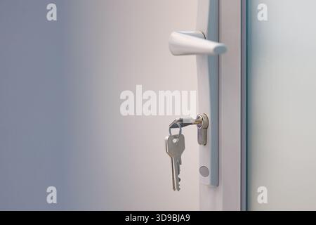 Türgriff mit Schlüssel in Schloss an moderner grauer Tür. Nahaufnahme eines Türgriffs und Schlüssels im Schloss, Symbol für Zugang, Sicherheit und Privatsphäre. Stockfoto