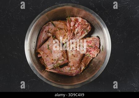 Zwei rohe Hinterbeine und Kaninchen marinieren mit Kräutern und Gewürzen in einer Metallschale. Es ist zum Kochen vorbereitet. Diese Szene fängt das wesentliche ein Stockfoto