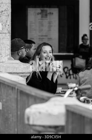 Emotionale Straßenszene mit einer Frau, die Kaffee hält und Authentizität, Einfachheit und menschliche Verbundenheit im urbanen Lifestyle ausdrückt Stockfoto