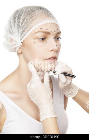 Nahaufnahme eines nicht erkennbaren plastischen Chirurgen, der Markierungen auf Frau', s Face.Studio shot, zeichnet Stockfoto