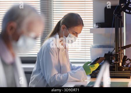 Junge Kaukasische Wissenschaftlerin, Die Laborgeräte Während Der Arbeit Bedient Stockfoto