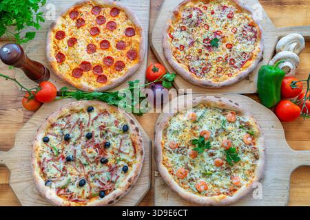 Verschiedene Gourmet-Pizzen mit verschiedenen Belägen auf Holzbrettern, mit lebhaften Farben und frischen Zutaten für kulinarische Genüsse Stockfoto