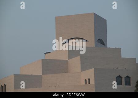 Besucher bewundern das einzigartige Design des Museums für Islamische Kunst in Doha, während die Dämmerung über der Stadt liegt und die atemberaubende Architektur zeigt. Stockfoto