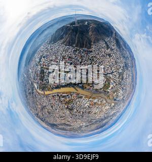 Aus der Vogelperspektive auf die Stadt, die sich unter dem Berg ausbreitet, mit dem Fernsehturm, der hoch steht, und dem Fluss, der durch die städtische Landschaft schneidet, Tiflis, T Stockfoto