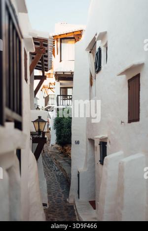 Kopfsteinpflasterallee zwischen weiß getünchten Häusern in Binibeca Vell, Menorca Stockfoto