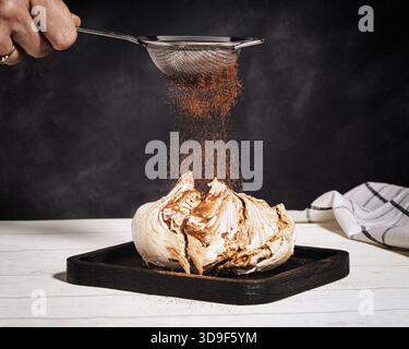kokospulver wird über einer Schokoladenschokolade gesiebt Stockfoto