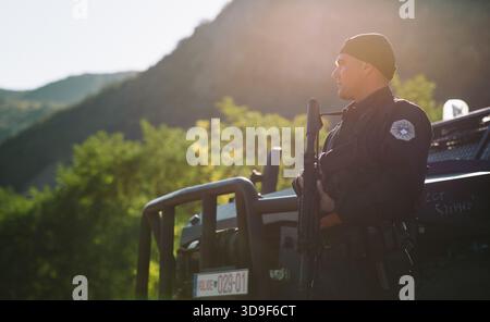 Ein kosovarischer Polizeibeamter steht während einer aktiven Sicherheitsoperation nach bewaffneten Auseinandersetzungen in der Nähe eines gepanzerten Fahrzeugs im Grenzgebiet Banjska Stockfoto