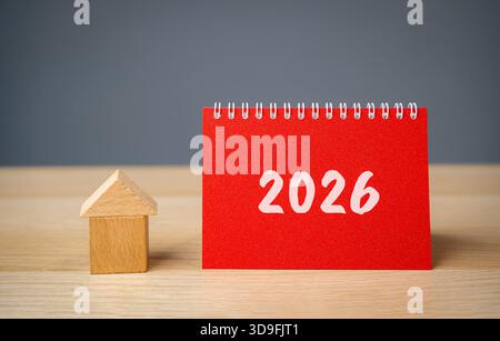 Inschrift 2026 und Miniaturhaus. Familienhaushaltsplanung für nächstes Jahr. Investitionen, Pläne, Einsparungen. Hypothekenzinsen. Immobilienkonzept. Refinanc Stockfoto