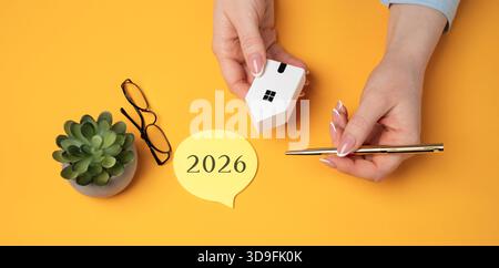 Familienhaushaltsplanung für nächstes Jahr. Investitionen, Pläne, Einsparungen. Hypothekenzinsen. Immobilienkonzept. Refinanzieren Sie das Heim. Inschrift 2026 und Miniatur Stockfoto