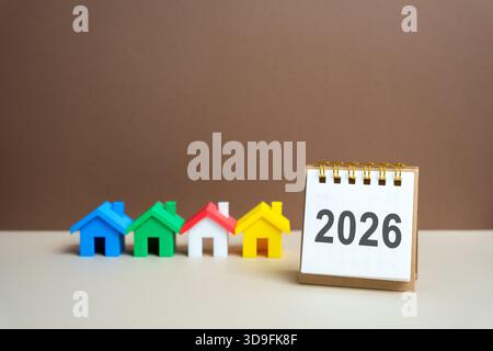 Inschrift 2026 und Miniaturhäuser. Familienhaushaltsplanung für nächstes Jahr. Investitionen, Pläne, Einsparungen. Hypothekenzinsen. Immobilienkonzept. Refinan Stockfoto