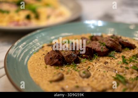 Risotto mit Fleischscheiben, serviert auf Teller. Es ist ein beliebtes italienisches Reisgericht. Stockfoto
