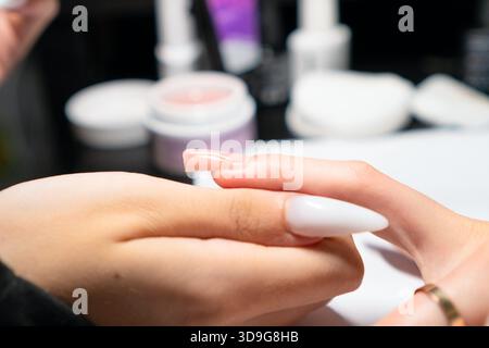 Professionelle Maniküre tragen bei der Nagelverlängerung sorgfältig gellack auf, um eine perfekte, gleichmäßige Abdeckung und Form zu gewährleisten. || Modell freigegeben Stockfoto