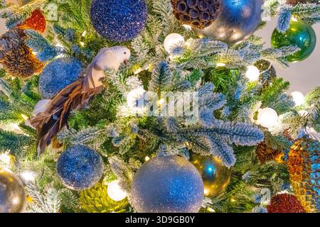 Nahaufnahme von blauen Ornamenten auf dem Weihnachtsbaum mit einem Vogelschmuck. Stockfoto